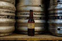 Load image into Gallery viewer, Beer bottle labeled 'The Kernel' in front of metal kegs with 'Kegstar' branding.