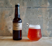 Load image into Gallery viewer, Bottle and glass of raspberry beie de saison from The Kernel Brewery on a wooden surface with a concrete wall background