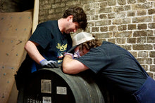 Load image into Gallery viewer, Two people working on a barrel against a brick wall.