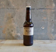 Load image into Gallery viewer, Beer bottle labeled 'The Kernel' on a wooden surface with a rustic background