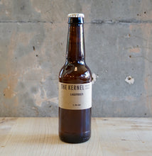 Load image into Gallery viewer, Brown beer bottle with 'The Kernel' label on a wooden surface and concrete wall background