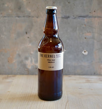 Load image into Gallery viewer, Beer bottle with 'The Kernel' label on a wooden surface and concrete wall background