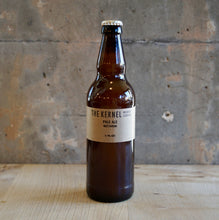 Load image into Gallery viewer, Beer bottle with 'The Kernel' label on a wooden surface and concrete wall background