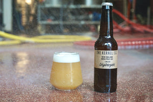 Beer bottle and glass on a reflective surface with a blurred background