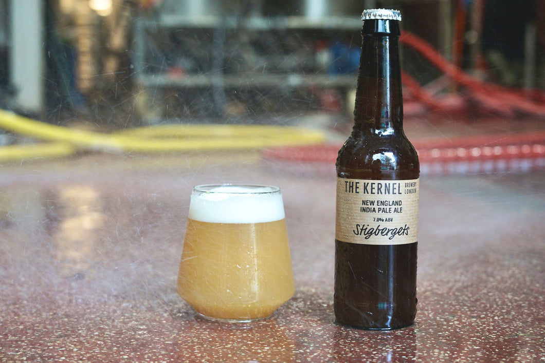 Beer bottle and glass on a reflective surface with a blurred background